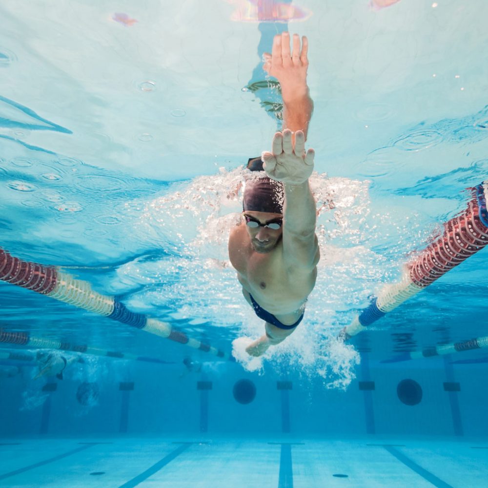 Professional man swimmer inside swimming pool. Underwater panoramic image.